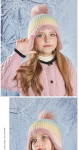 Detail of children's rainbow knit hat with pink faux fur trim and pom-pom in snow