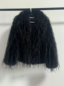 Close-up detail of the premium black faux fur texture on a cropped fringe jacket