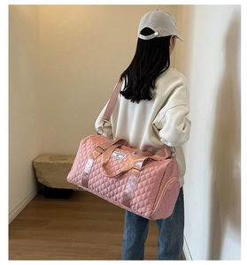Détail du sac de voyage matelassé rose montrant les poignées et le tissu imperméable