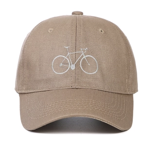 Close-up of embroidered white bicycle design on a khaki cotton twill baseball cap