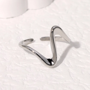 Minimalist silver wavy open ring with a polished metallic finish on a textured stone surface