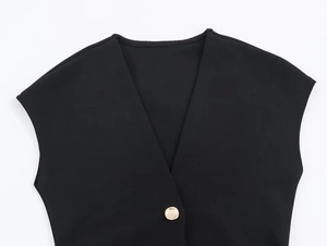 Close-up of black V-neck dress fabric with a single elegant gold button detail