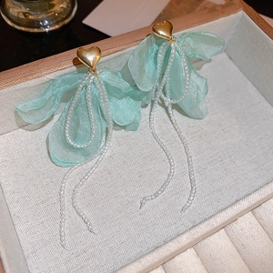 Dettaglio di petali in tulle verde menta e nappe di perline su orecchini a cuore oro
