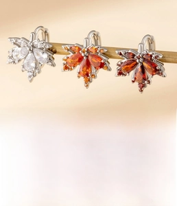Detail showing copper maple leaf earrings with zircon inlay and 10mm inner diameter