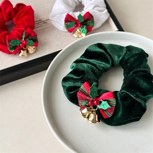Close-up of velvet Christmas hair scrunchies with plaid bows and golden bells detail