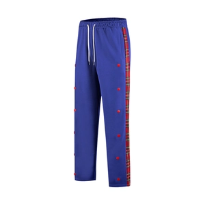 Close-up of navy blue trousers featuring side red-green plaid tape and decorative red buttons