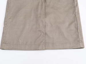 Detail of light khaki woven fabric showing fine checkered pattern and clean hem stitching