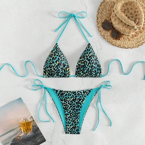 Flat lay of teal leopard print bikini set with straw hat and sunglasses on marble background