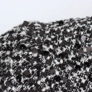 Macro shot of black and white tweed fabric texture with decorative sequins detail