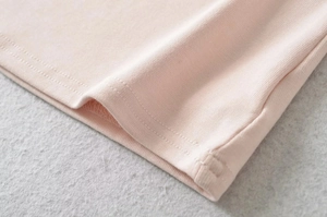 Macro detail of high-quality pink knit fabric with smooth stitching and double-needle hem