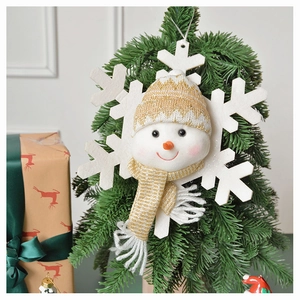 Detail of plush snowman ornament on green Christmas tree branch with knit hat and felt snowflake