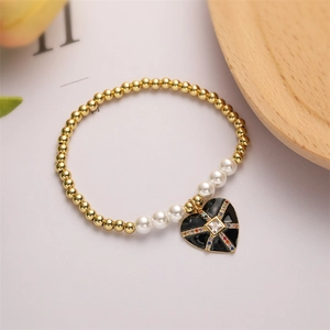 Dettaglio del bracciale con perle bianche e ciondolo a cuore in smalto nero con gemme