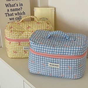 Close-up of quilted plaid cosmetic bags with bow detail and pink zipper closure