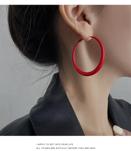 Close-up of minimalist matte red hoop earrings on a model with a black leather jacket
