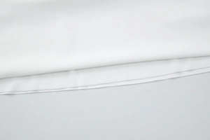Close-up of white fabric texture and side pleated stitching detail on a sexy backless dress