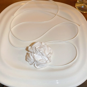 Détail d'un collier fleur en tissu blanc de style vintage français sur une assiette
