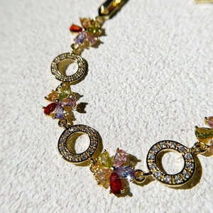 Macro detail of gold-plated bracelet with multi-color zircon flower charms and water-drop gems