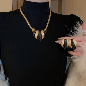 Model wearing vintage gold and black enamel jewelry set with necklace and stud earrings
