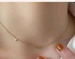 Primer plano de collar de acero inoxidable dorado con tres corazones en una modelo
