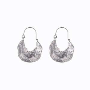 Macro shot of silver crescent earrings featuring intricate vintage embossed textures