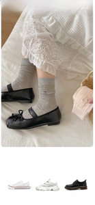 Detail of gray ribbed cotton socks with bow embroidery styled with black Mary Jane shoes