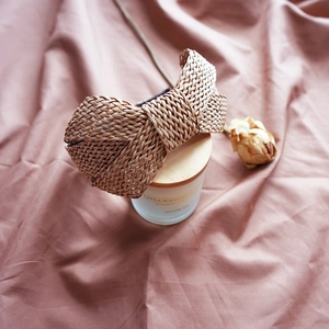 Detailed texture of brown raffia woven headband with large bow on pink fabric