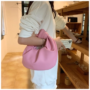 Close-up of pink ruched cloud bag with knotted handle and elegant silver chain detail