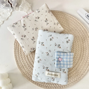 Detail of floral corduroy book cover featuring Sozakka label and small plaid pouch