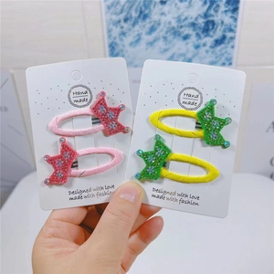 Close-up of pink and yellow crown hair clips with sequins on display cards