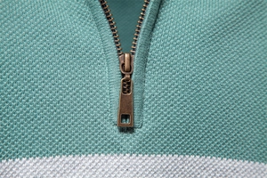 Details des Kupferreißverschlusses und der mintgrünen gestreiften Stricktextur