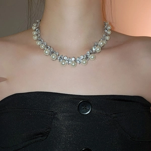 Close-up of elegant pearl necklace with sparkling diamonds on female model's neck