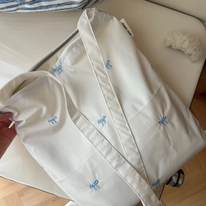 Détail de broderie nœud bleu et étiquette simple wish sur un sac en coton blanc