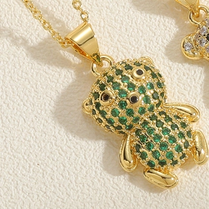 Detailed macro view of a gold bear pendant with sparkling green cubic zirconia stones