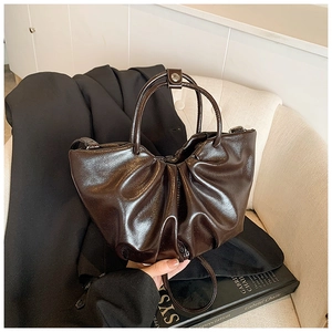Detailed close-up of dark brown pleated leather bag with circular handles on blazer
