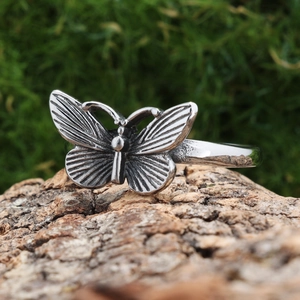 Vintage silver butterfly ring with textured wings on a natural bark display stand