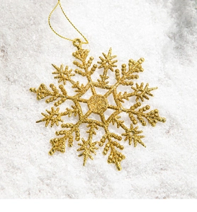 Close-up of golden glittery snowflake ornament with hanging string on white background