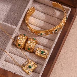 Detail of gold evil eye jewelry set with green malachite and hammered texture finish