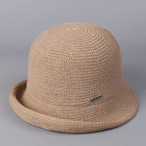 Close-up of beige knit sun hat detail with gold Pretty Lady brand metal plaque