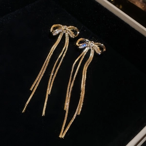 Details von goldenen Schleifenohrringen mit Zirkonia und langen Schlangenketten