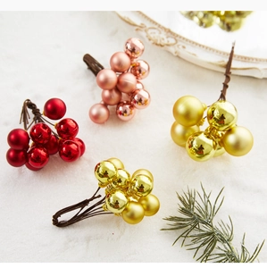 Detail of glittery red and gold Christmas berry stems with glossy and matte finish bulbs