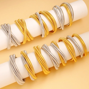 Detail of spiral spring multi-layered bracelets in gold and silver finish on white stand