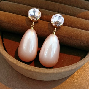 Détail macro de boucles d'oreilles dorées avec pierre œil de chat rose et cristal