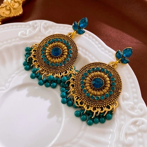 Détail macro de boucles d'oreilles vintage avec cristaux bleus et pompons perlés