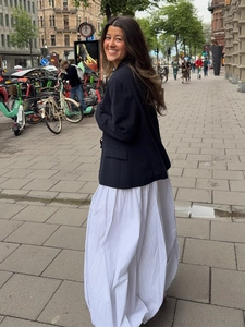 Deep blue single-breasted blazer paired with white flowing maxi skirt in urban street view