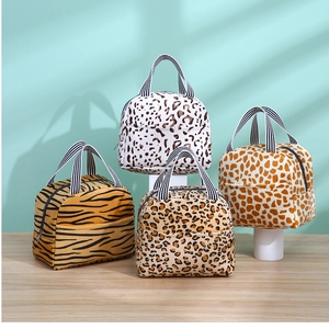 Détail de quatre sacs à lunch aux motifs animaliers avec poignées rayées sur socles