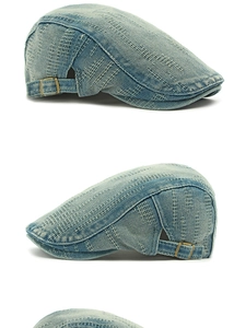 Detail of washed denim flat cap showing white stitching and side metal buckle