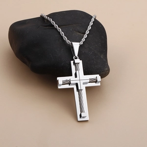 Detail of cross pendant with woven steel wire inlay on black pebbles background
