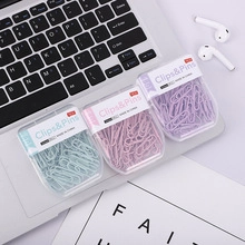 Detailed view of pastel blue, pink and purple paper clips in plastic boxes on a desk