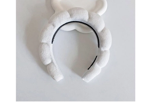 Top-down view of white sponge braided headband on cloud-shaped prop with plush texture