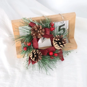 Christmas wreath with red black plaid bow, pine cones, berries on a wooden stand